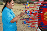 Young adult standing at a target that is full of arrows
